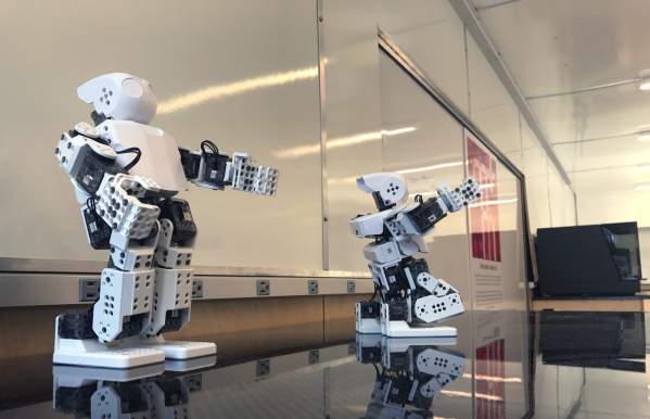 Two white robots on top of a black table.