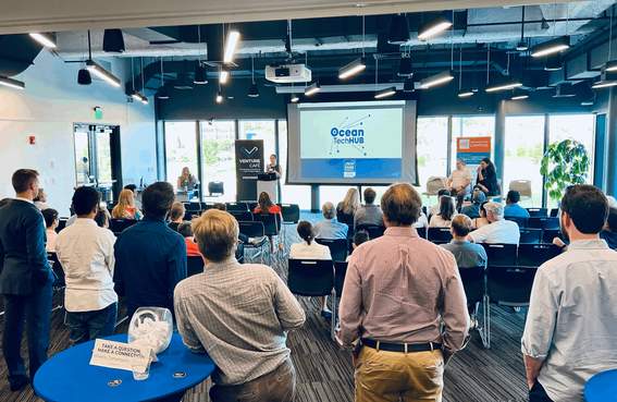 A room full of people looking at a presentation on a projector.